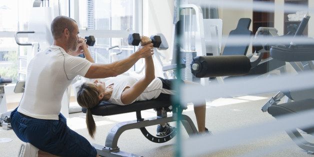 personal trainer helping woman work out