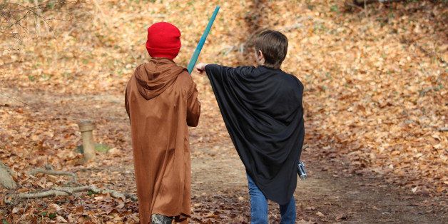 Two little boys dressed up in costumes and playing with pretend swords as they walk along a trail. Friendship. Childhood. Imagination.
