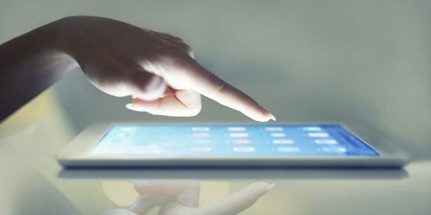 Cropped closeup of a woman's hand above a digital tablet