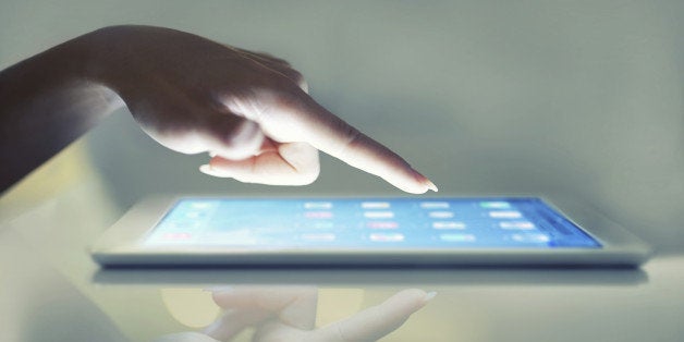 Cropped closeup of a woman's hand above a digital tablet