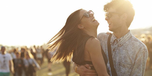 Friends hanging out at big outside music festival, in the sunset.