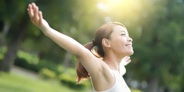 Carefree and free cheering woman in the park. girl raising her arms up smiling happy. asian beauty