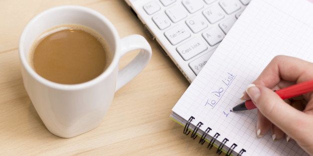 Woman writing a 'to do list' at her desk with a cup of fresh coffee