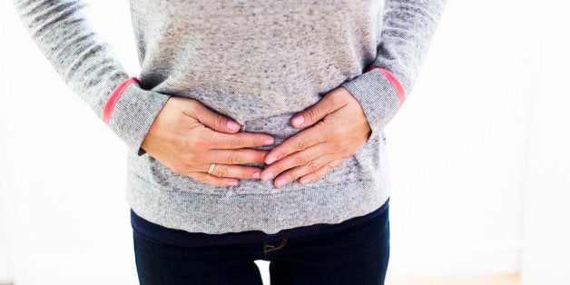 Unrecognizable woman with stomach ache pressing on the stomach