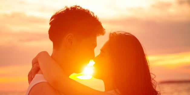 young couple kissing at sunset on beach