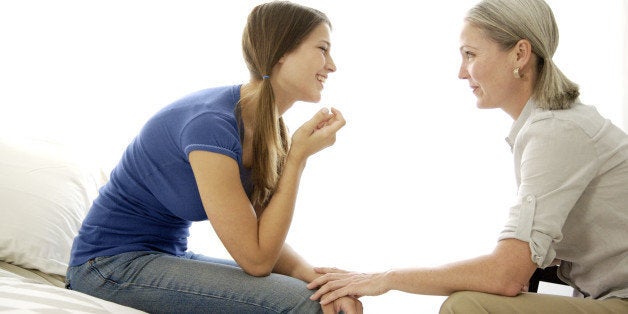 Mature mom and teenage daughter talking, bonding, and smiling with each other