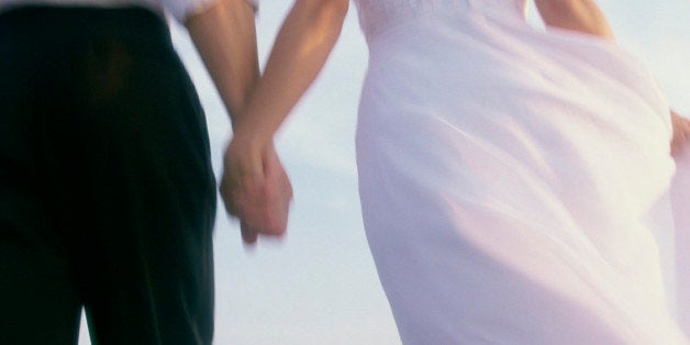 Rear view of a newlywed couple walking on the beach