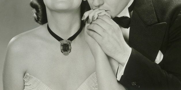 Gentleman kissing hand of elegant woman, studio shot