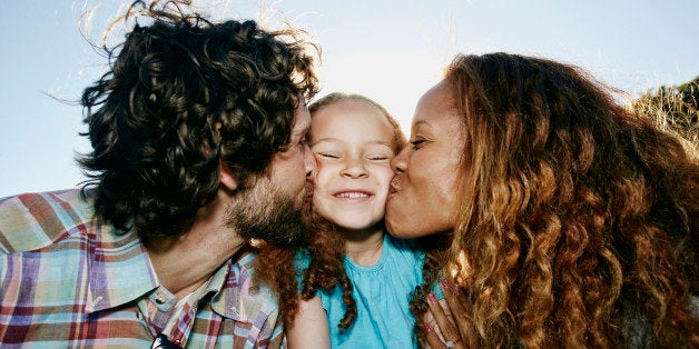 Parents kissing cheeks of daughter outdoors