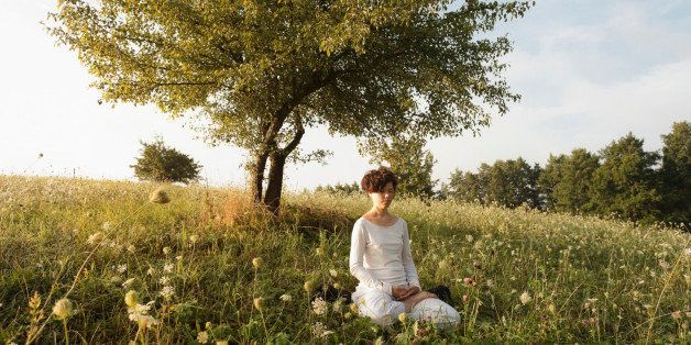 Woman meditating on grassy field