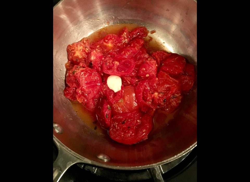 Slow-roasted tomatoes in a saucepan with one clove of garlic