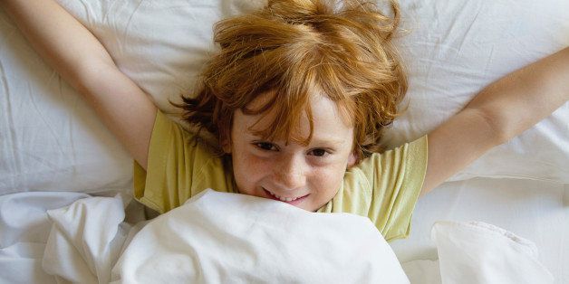 Boy lying in bed with arms outstretched