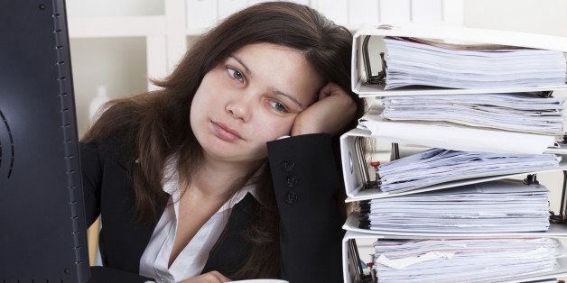 Stressed Businesswoman Working In Office With Stack Of Folders