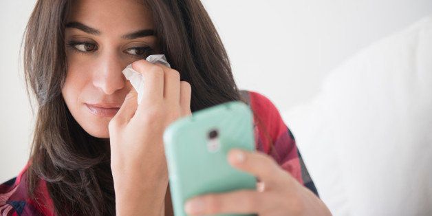Sad woman crying and using cell phone