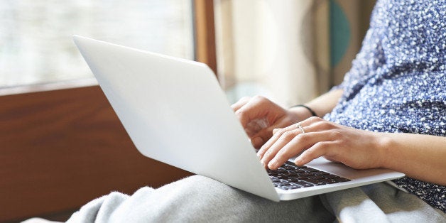 Woman using laptop at home, close up.