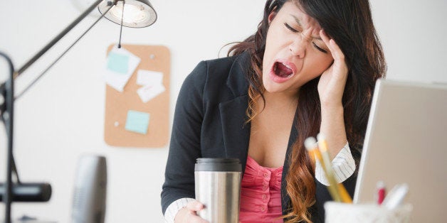 Pacific Islander businesswoman yawning at desk