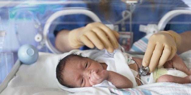 Female doctor examining newborn baby in incubator