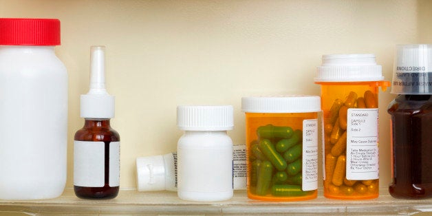 Several containers of over the counter and prescription medications on the shelves of a 1960's medicine cabinet.