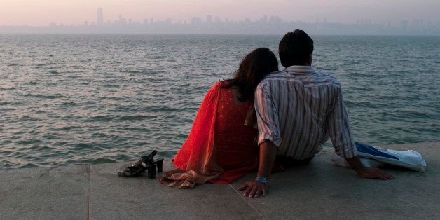 An Indian couple enjoy a sunset view from Marine Drive in Mumbai, India.