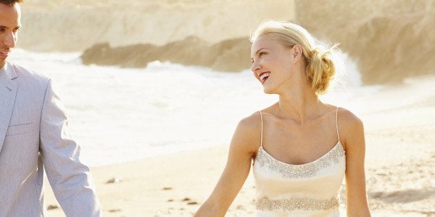 Newlywed couple walking on beach