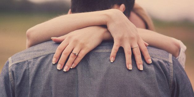 A woman embracing her man with engagement ring on hand.