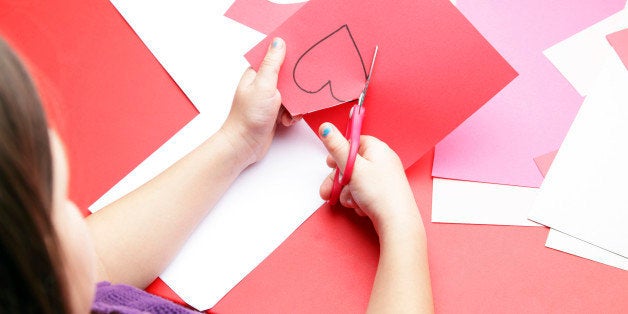 A young girl cuts out a paper heart to use for her Valentine's Day card.
