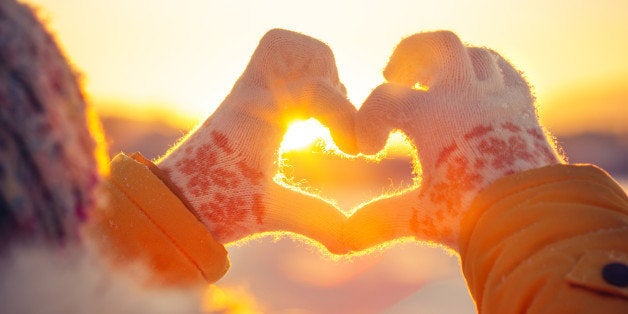 Woman hands in winter gloves Heart symbol shaped Lifestyle and Feelings concept with sunset light nature on background