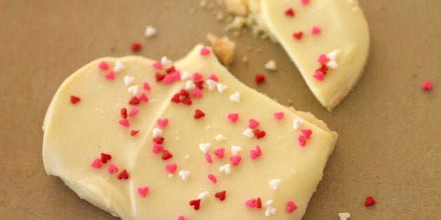 A heart shaped Valentine's Day cookie with sprinkles that is broken in half