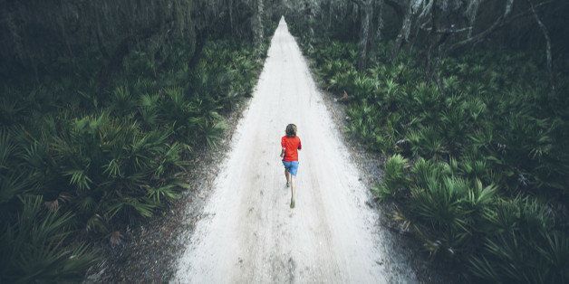 A solitary male runner out for a training run on rural road at sunset on Cumberland Island off the coast of Georgia.