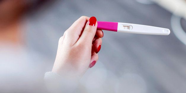 Woman holding a positive pregnancy test.