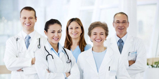 Group of cheerful doctors standing together and looking at camera.