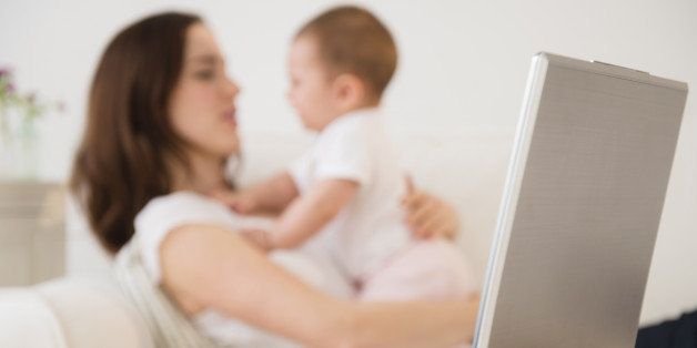 Laptop and cell phone beside mother with baby