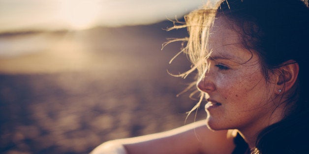 Portrait of a blond haired woman with smartwatch at the beach after running.