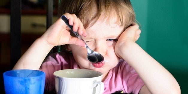 Nervous little boy eating and drinking milk