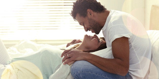 Loving interracial couple on their bed about to kiss each other.