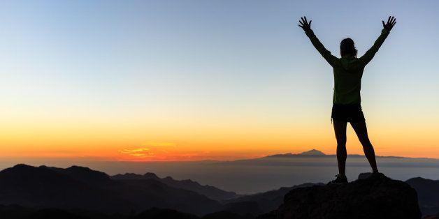 Woman successful hiking climbing silhouette in mountains, motivation and inspiration in beautiful sunset and ocean. Female hiker with arms up outstretched on mountain top looking at beautiful night sunset inspirational landscape.