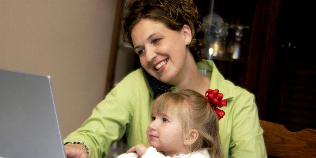 Mom working at home while holding daughter