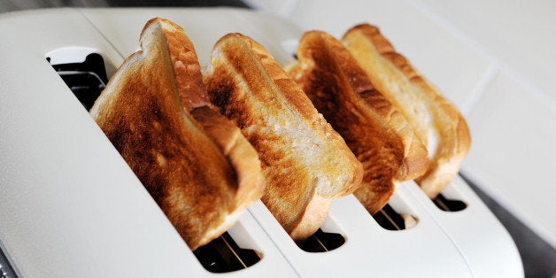 Four slices of white toasted bread in a four slice toaster.