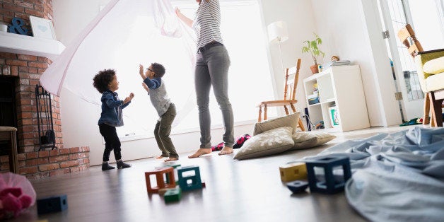 Children dancing under mother with sheet