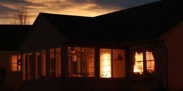 Looking into a house as the sun goes down. Lights inside duplicate sky lights behind. Warm glow of home.