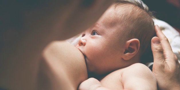 Mother holding and breast-feeding little baby