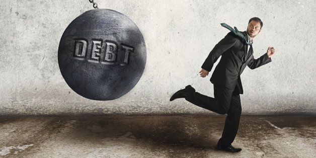young businessman running away from the wrecking ball, as the symbol of debt