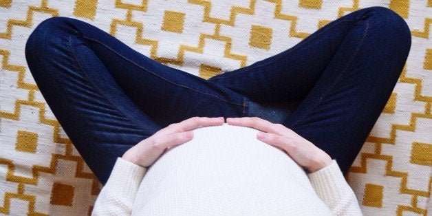 High Angle View Of Pregnant Woman Sitting On Bed