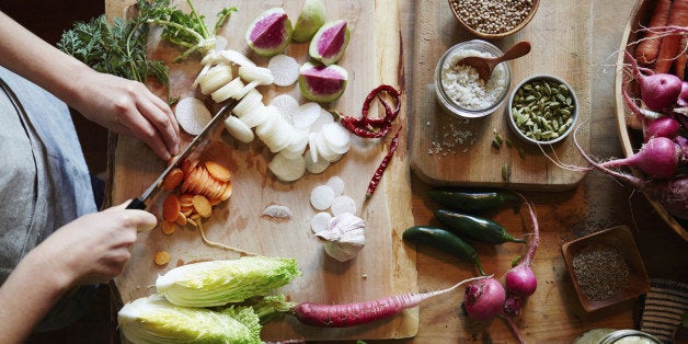 Woman cooking in kitchen with ingredients around her