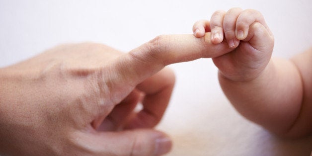 baby's small hand holding father's finger