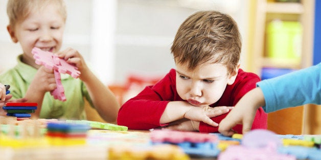 Small angry looking boy looking at the toys. 