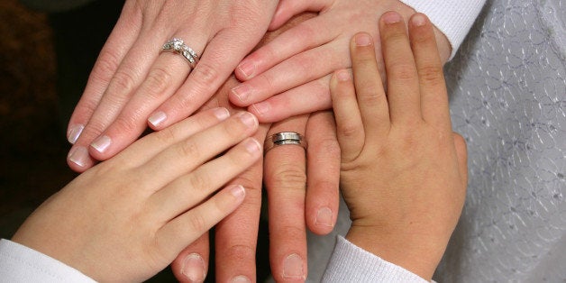 A new family at the wedding, blending Mom and her two children with Dad and his child, making a new family with stepchildren. The husband and wife are wearing rings.