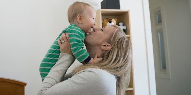 Mother kissing and cuddling happy baby boy