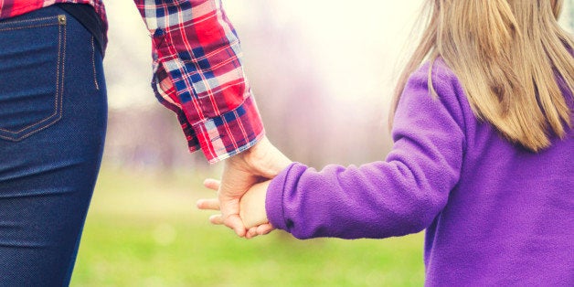 Mother is walking with her daughter in the park and holding hands. A closeup, rear view, AdobeRGB profile.