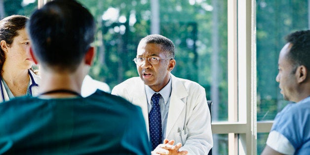 Mature male doctor leading discussion in medical team meeting in conference room in hospital